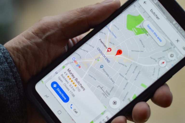 Dłoń trzymająca telefon z otwartymi mapami Google i wynikami lokalnych firm