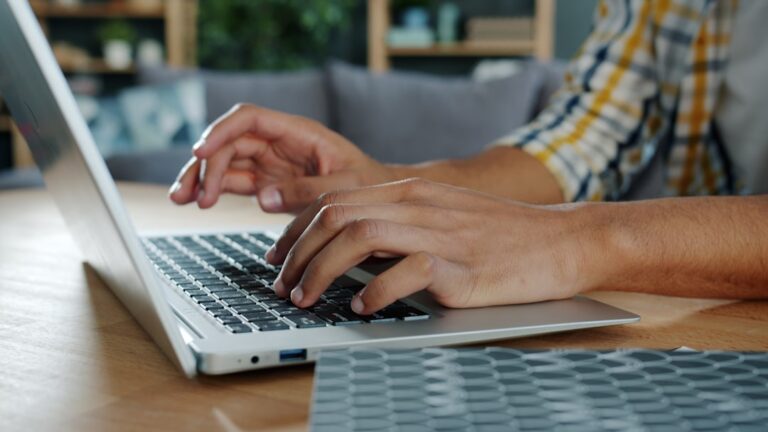 Dłonie piszące wiadomość na klawiaturze laptopa